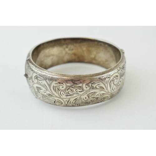 340 - Vintage silver bangle with hand chased repeated design and safety chain. Weight 42.6 grams.