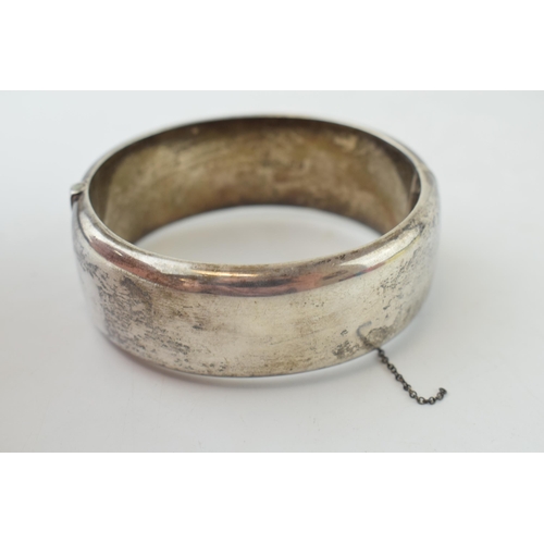 340 - Vintage silver bangle with hand chased repeated design and safety chain. Weight 42.6 grams.