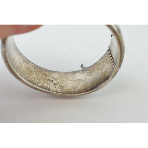 340 - Vintage silver bangle with hand chased repeated design and safety chain. Weight 42.6 grams.