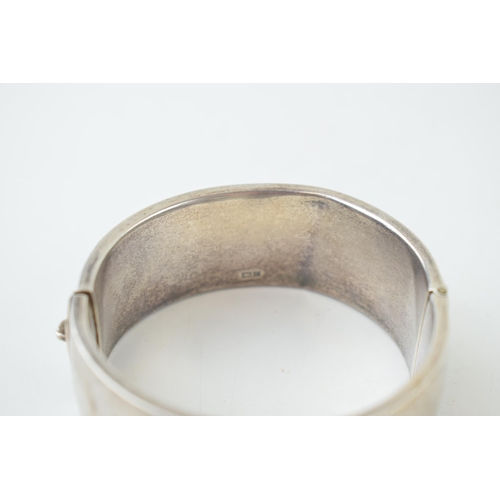 341 - Vintage silver bangle with hand chased repeated design. Weight 35.1 grams.