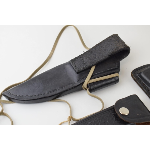 67 - A collection of leather knife belt pouches and sheaths together with three Marksman knives. (Qty)