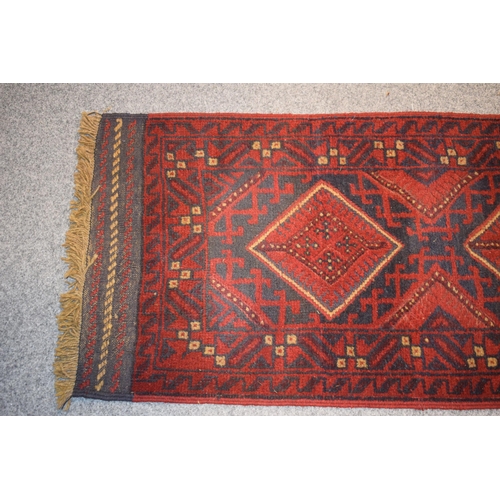 214 - A Middle Eastern runner rug in blue, reds and cream. Length 268cm x 65cm.