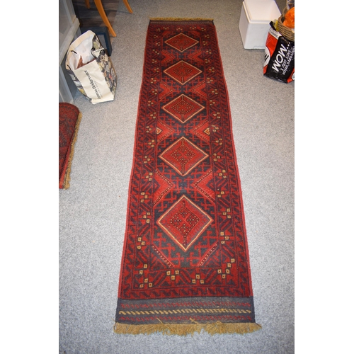 214 - A Middle Eastern runner rug in blue, reds and cream. Length 268cm x 65cm.