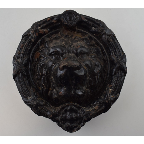 245 - A cast iron door knocker in the form of a lions head. 22cm diameter.