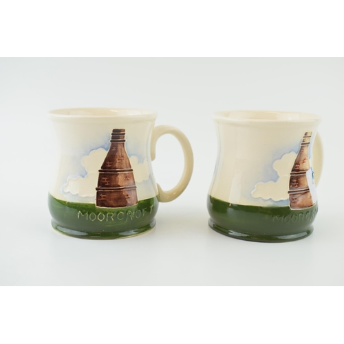 32 - A pair of Moorcroft Pottery mugs with Staffordshire pot bank design. (2) Height 9cm.