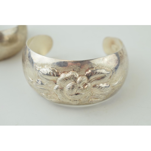 518 - Two sterling silver bangles, on with floral repousse decoration, 55.3g (2).