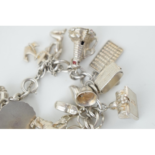 580 - Silver charm bracelet to include the Eiffel Tower, cupid, rings, a tankard and others, 79.5g.