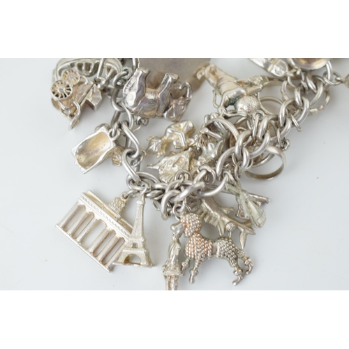 580 - Silver charm bracelet to include the Eiffel Tower, cupid, rings, a tankard and others, 79.5g.