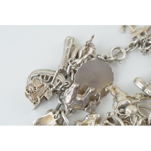 580 - Silver charm bracelet to include the Eiffel Tower, cupid, rings, a tankard and others, 79.5g.