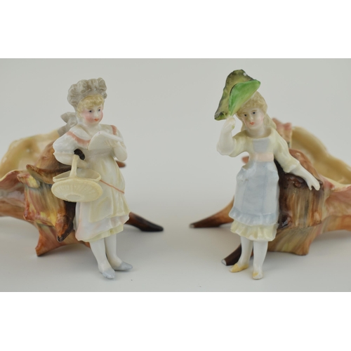 101 - A pair of late 19th / early 20th century pottery figures of children sat on elongated sea shells, un... 