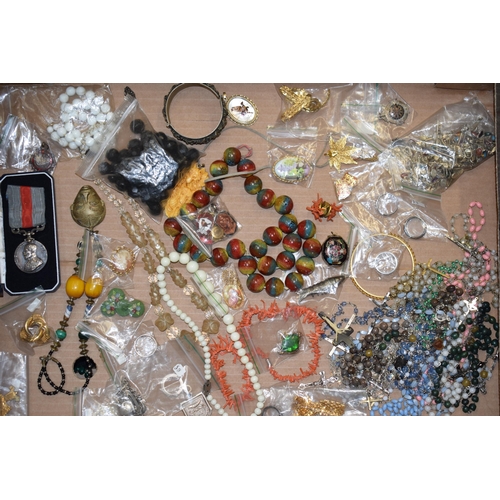 592 - A collection of costume jewellery to include a medal, bangles, a multicoloured glass necklace, rings... 