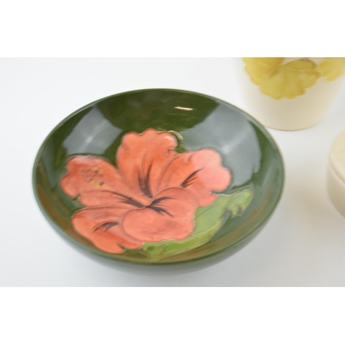 86 - Moorcroft to include a green hibiscus bowl with two light coloured items, tallest 18.5cm tall (3).