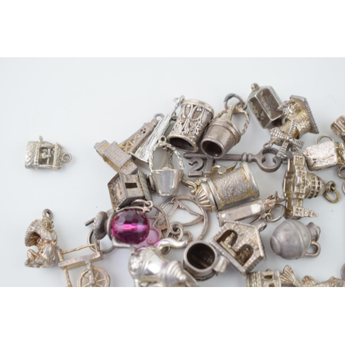 556 - A collection of silver charms to include kettles, cars, buildings and others, 168.5g.