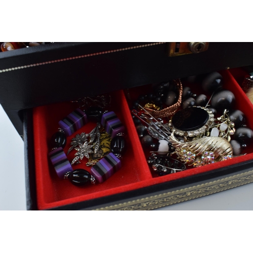 568 - A jewellery box of costume jewellery to include a metal albert watch chain with a silver fob, a Jady... 