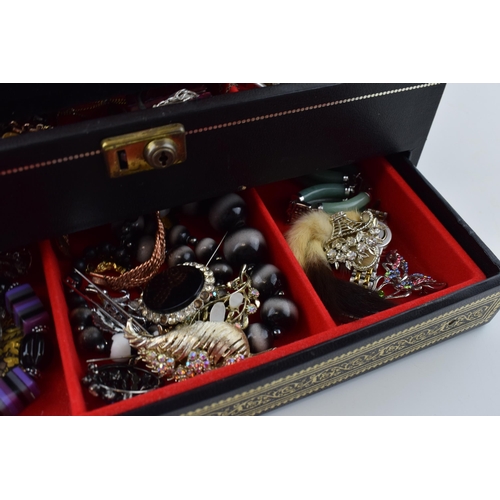 568 - A jewellery box of costume jewellery to include a metal albert watch chain with a silver fob, a Jady... 