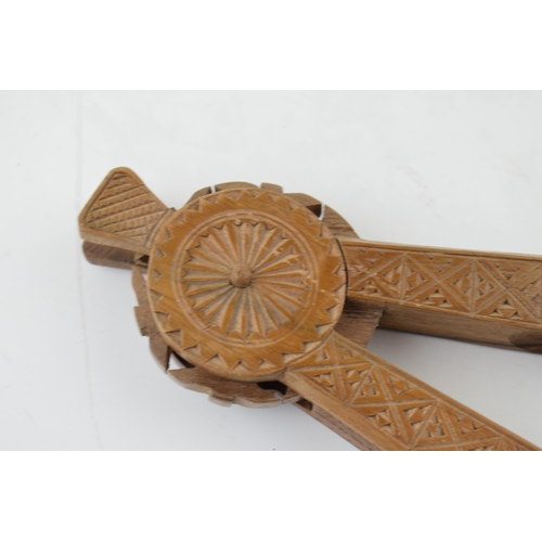 386 - 20th century treen nut cracker, carved decoration, 22cm long.