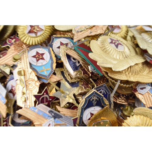 445 - A large collection of military cap badges and ribbons predominantly of Russian origin. (Qty)