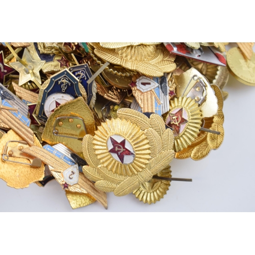 445 - A large collection of military cap badges and ribbons predominantly of Russian origin. (Qty)