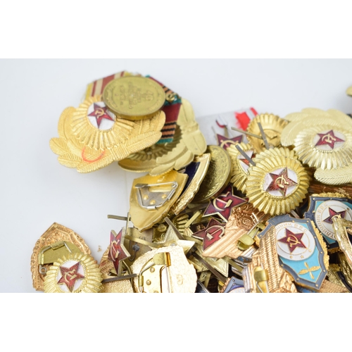 445 - A large collection of military cap badges and ribbons predominantly of Russian origin. (Qty)