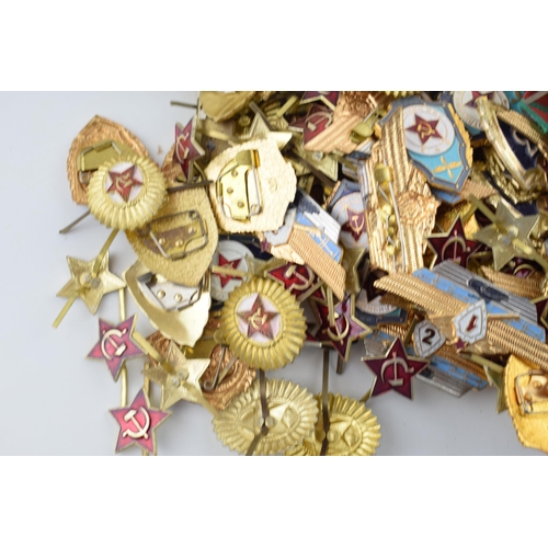 445 - A large collection of military cap badges and ribbons predominantly of Russian origin. (Qty)