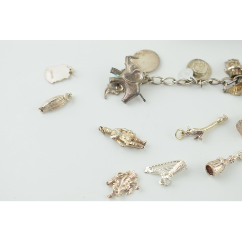 546 - A silver charm bracelet together with a quantity of loose charms. 56.9 grams.