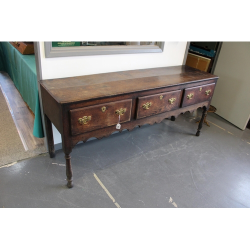 42 - Late 18th / early 19th century oak dresser base, three drawers, turned legs, brass handles and escut... 