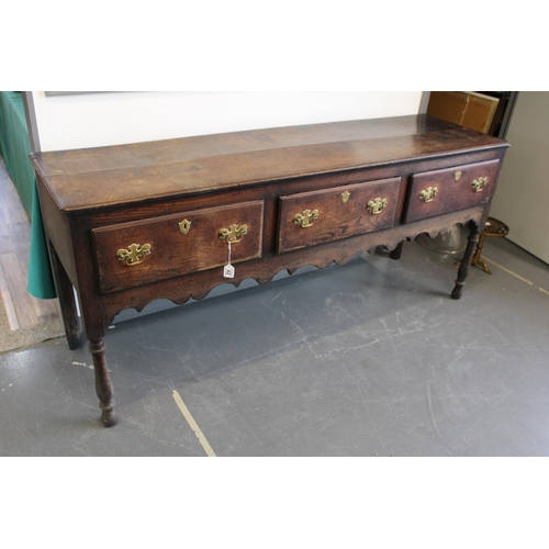 42 - Late 18th / early 19th century oak dresser base, three drawers, turned legs, brass handles and escut... 