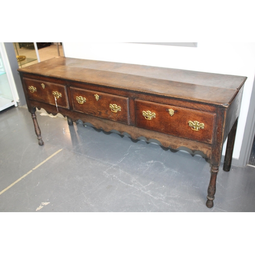 42 - Late 18th / early 19th century oak dresser base, three drawers, turned legs, brass handles and escut... 