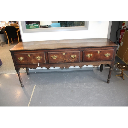 42 - Late 18th / early 19th century oak dresser base, three drawers, turned legs, brass handles and escut... 