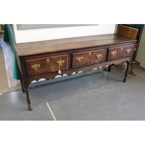 42 - Late 18th / early 19th century oak dresser base, three drawers, turned legs, brass handles and escut... 