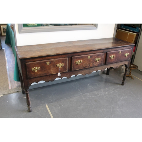 42 - Late 18th / early 19th century oak dresser base, three drawers, turned legs, brass handles and escut... 