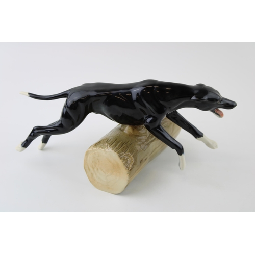 51 - Elite Pottery figure of a whippet leaping over a log (unmarked), 25cm long.