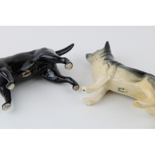 86 - Two small Beswick dogs to include a black labrador and an alsatian (2).