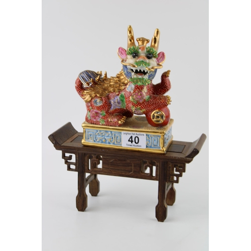 40 - Contempory Chinese Fu Dog ceramic figure on wooden stand. Height 30cm.