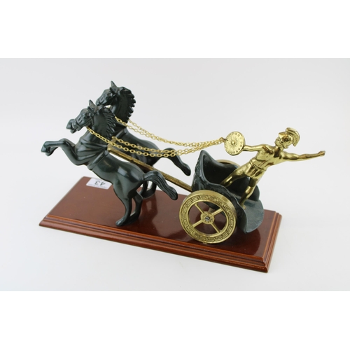 43 - A cast metal figure of a Roman warrior in horse drawn chariot on plinth. Height 20cm.