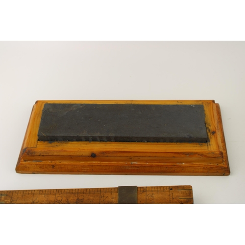 145 - An early treen shoe / foot measure together with a spirit level and a cased wet stone. (3)