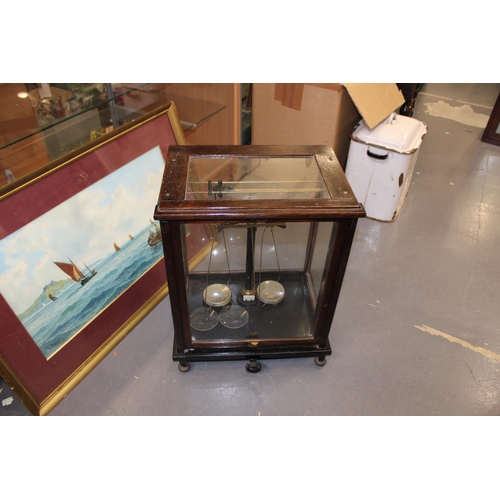 383 - Cased set of scientific weighing scales, indistinct maker, glass and wooden case, sliding door.