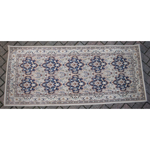 394 - A Persian style runner / rug carpet in blues and creams. Dimensions 182cm x 80cm.