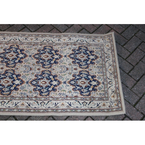 394 - A Persian style runner / rug carpet in blues and creams. Dimensions 182cm x 80cm.