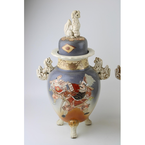 397 - A pair of Early 20th century Satsuma vases Fu Dog finials to lid, ornate handles, raised on three le... 