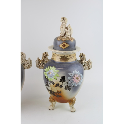 397 - A pair of Early 20th century Satsuma vases Fu Dog finials to lid, ornate handles, raised on three le... 