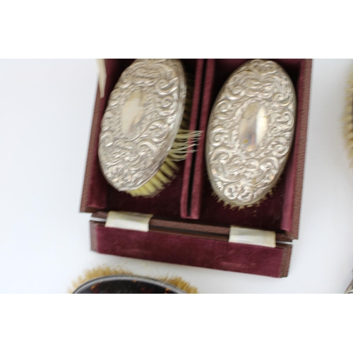 593 - A collection of silver brushes to include two matching examples in box, a silver pique tortoiseshell... 