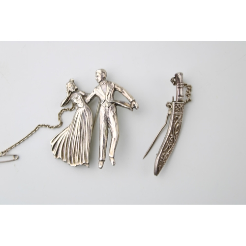 604 - Two silver brooches to include a couple dancing and a dagger (2), 18.6g.