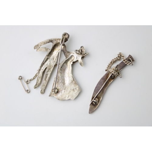 604 - Two silver brooches to include a couple dancing and a dagger (2), 18.6g.