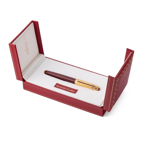 247 - Cartier, Pasha de Cartier, a roller ball pen, with gold plated ribbed cap, red cabochon and burgundy... 