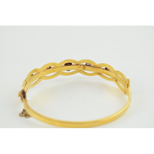 322 - Yellow metal (tests as 9ct gold or higher) bangle, set graduated Amethyst stones with safety chain i... 