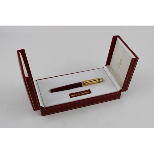 247 - Cartier, Pasha de Cartier, a roller ball pen, with gold plated ribbed cap, red cabochon and burgundy... 