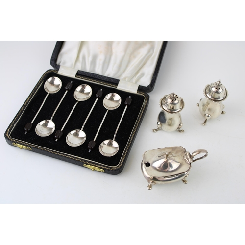 279 - A set of six silver coffee spoons with coffee bean finials, and a cruet set comprising salt and pepp... 