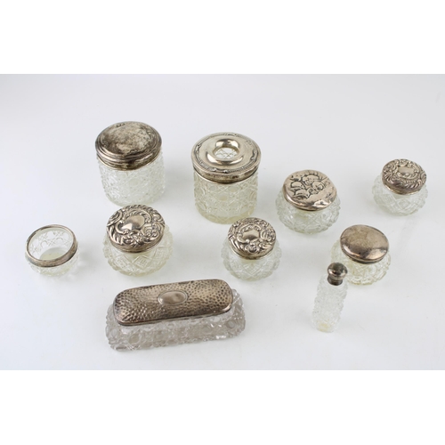 315 - A collection of silver topped glass jars and similar to include a perfume bottle, toilet jars, an op... 