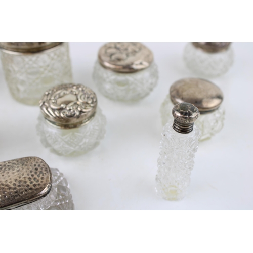 315 - A collection of silver topped glass jars and similar to include a perfume bottle, toilet jars, an op... 